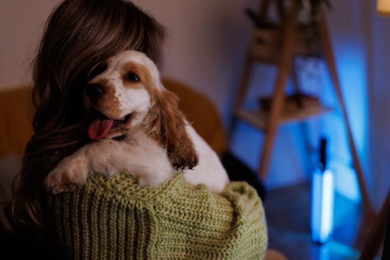 Photo of a woman’s first night with her new puppy. She is holding the puppy in a dark room.